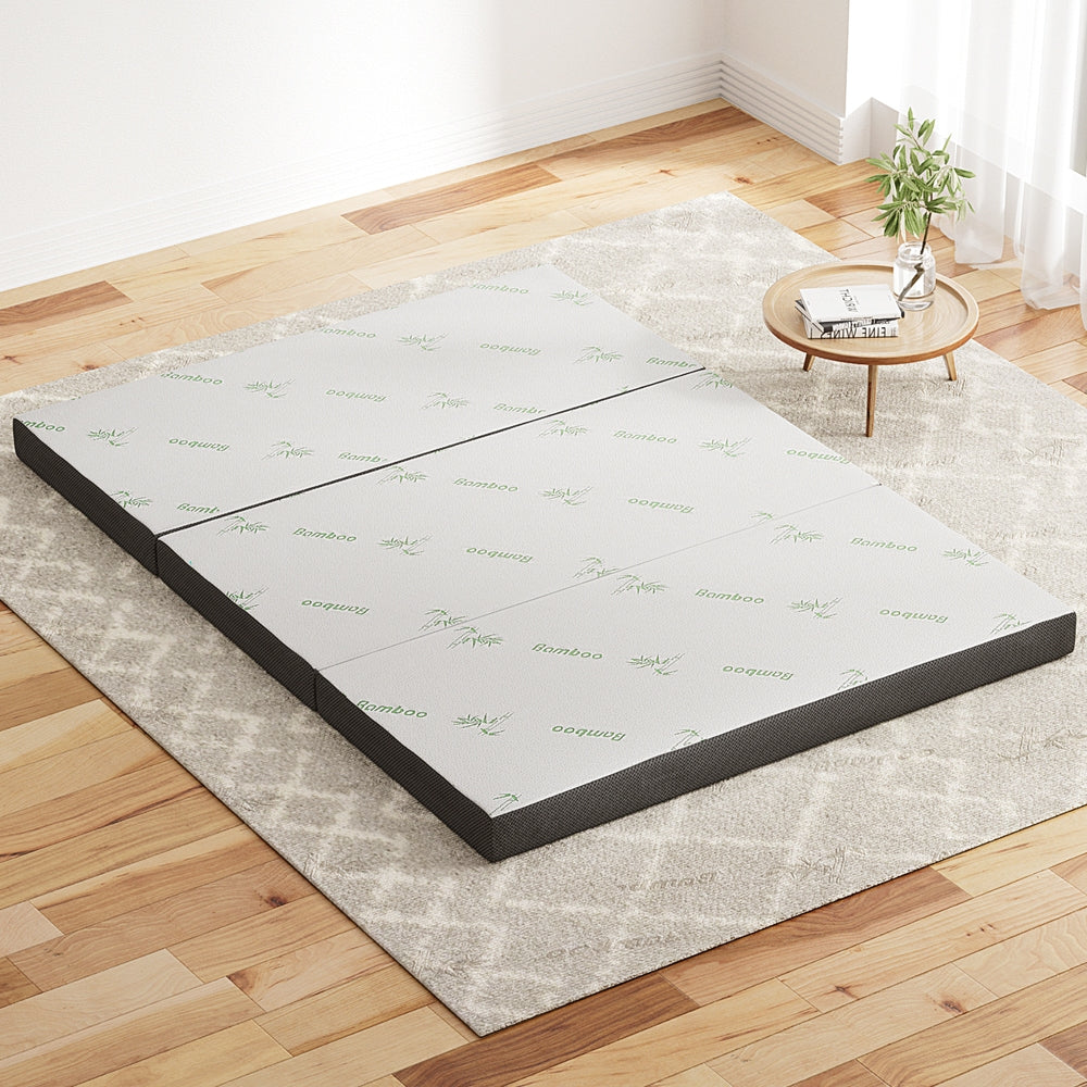 Mattress base on a wooden floor with a small table and plant in the background