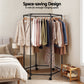 Clothing rack with clothes in a bedroom setting, emphasizing space-saving design.