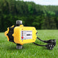 Yellow and black pump control device on grass with blurred greenery in the background