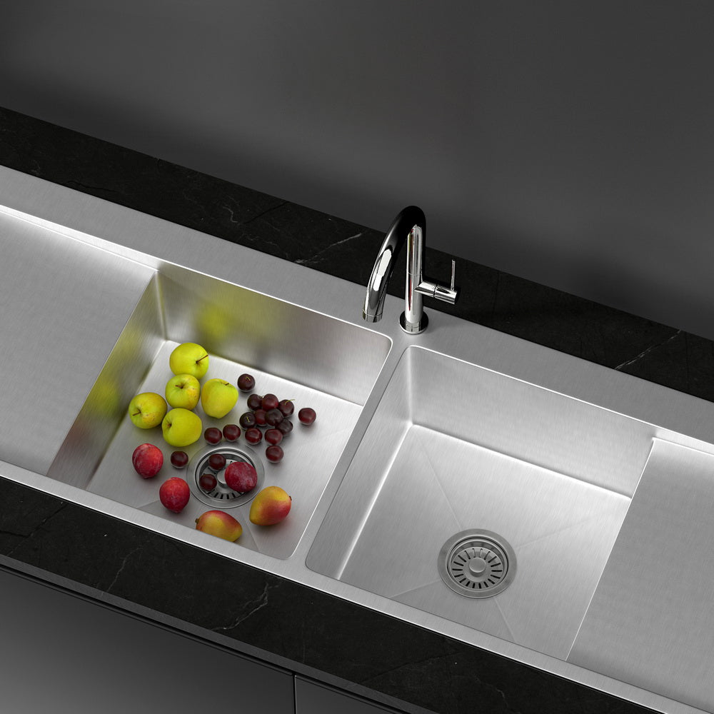 Stainless steel kitchen sink with fruits on a dark countertop