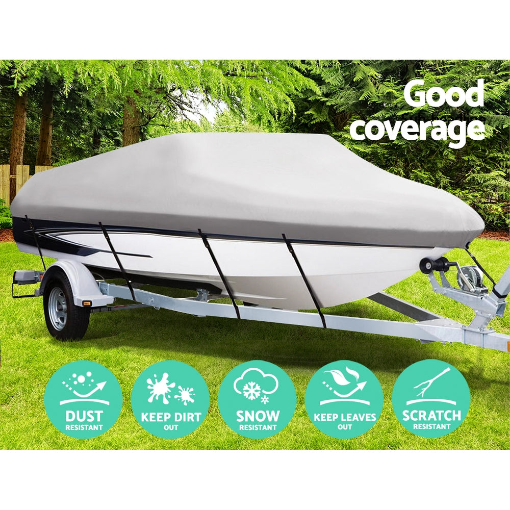 Boat covered with a protective cover on a grassy area with trees in the background.