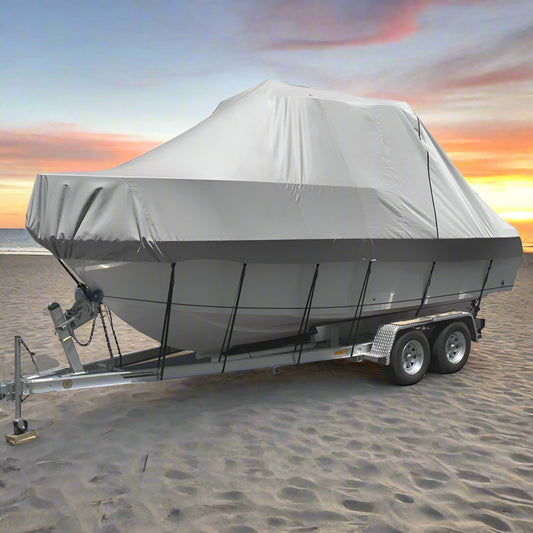 Boat on a trailer with a gray cover on a sandy beach with ocean in the background
