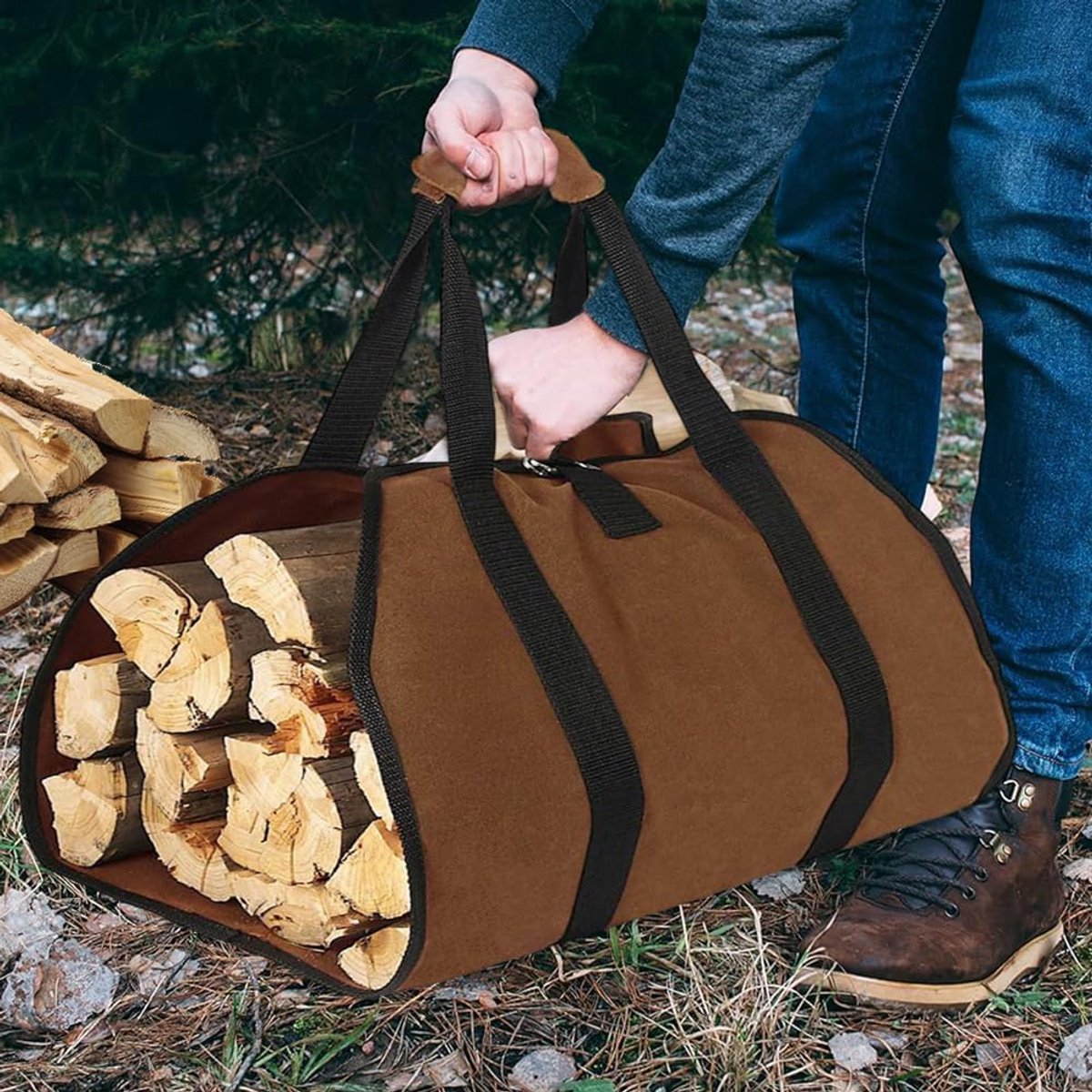 Brown duffel bag filled with firewood being carried by a person outdoors.